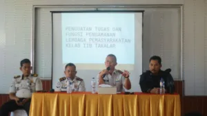 Kepala Lapas Kelas IIB Takalar Andi Gunawan memegang mikrofon saat memberikan penguatan tugas dan fungsi pengamanan di depan layar proyektor bersama jajaran pejabat struktural