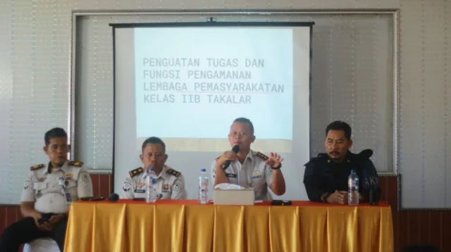 Kepala Lapas Kelas IIB Takalar Andi Gunawan memegang mikrofon saat memberikan penguatan tugas dan fungsi pengamanan di depan layar proyektor bersama jajaran pejabat struktural
