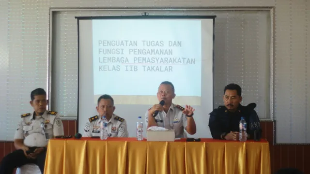 Kepala Lapas Kelas IIB Takalar Andi Gunawan memegang mikrofon saat memberikan penguatan tugas dan fungsi pengamanan di depan layar proyektor bersama jajaran pejabat struktural