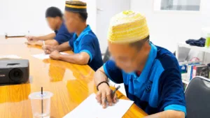 Warga binaan Lapas Takalar memakai peci sedang serius belajar membaca dan menulis di ruang kelas keaksaraan fungsional