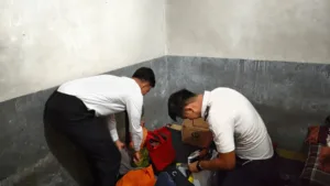 Dua petugas Lapas Kelas IIB Takalar berpakaian kemeja putih sedang melakukan penggeledahan dan memeriksa tas pakaian warga binaan di sudut kamar blok hunian