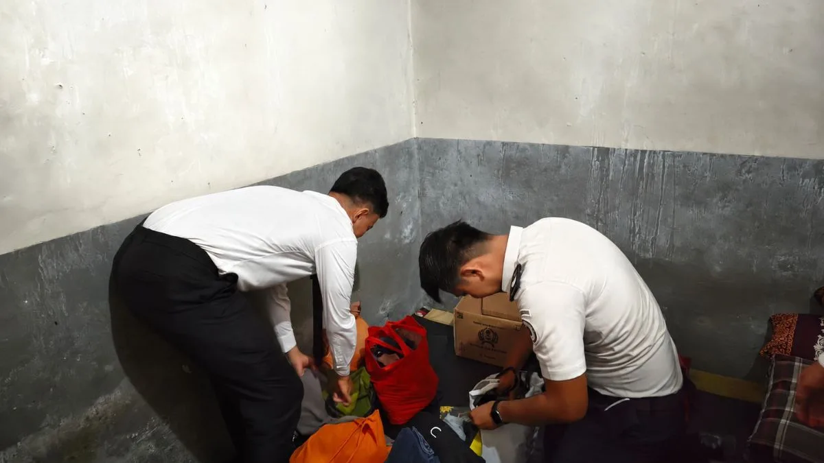 Dua petugas Lapas Kelas IIB Takalar berpakaian kemeja putih sedang melakukan penggeledahan dan memeriksa tas pakaian warga binaan di sudut kamar blok hunian