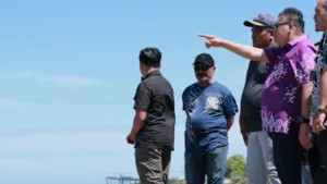 Bupati Takalar Mohammad Firdaus Daeng Manye didampingi jajaran pemerintah desa berdiri di pinggir pantai menunjuk ke arah laut lepas saat meninjau langsung kawasan Punaga Beach